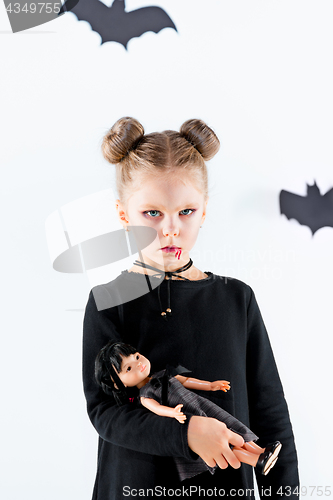 Image of Little girl witch in black dress over magical accessories. Halloween, the studio evening.