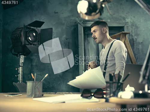 Image of Portrait of a bearded businessman who is checking details of his upcoming meeting in his notebook and typing.