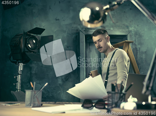 Image of Portrait of a bearded businessman who is checking details of his upcoming meeting in his notebook and typing.