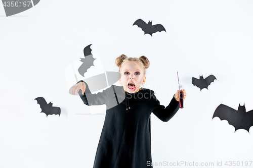 Image of Little girl witch in black dress over magical accessories. Halloween, the studio evening.