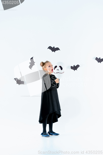 Image of Little girl witch in black dress over magical accessories. Halloween, the studio evening.