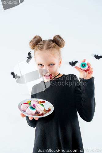 Image of Little girl witch in black dress over magical accessories. Halloween, the studio evening.