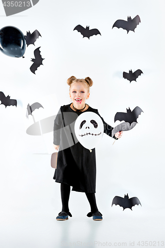 Image of Little girl witch in black dress over magical accessories. Halloween, the studio evening.