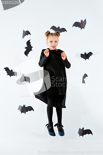 Image of Little girl witch in black dress over magical accessories. Halloween, the studio evening.