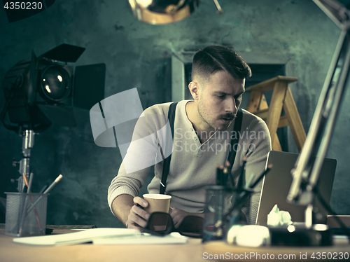 Image of Portrait of a bearded businessman who is checking details of his upcoming meeting in his notebook and typing.