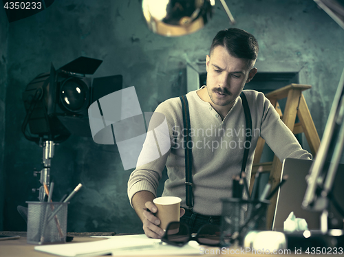 Image of Portrait of a bearded businessman who is checking details of his upcoming meeting in his notebook and typing.