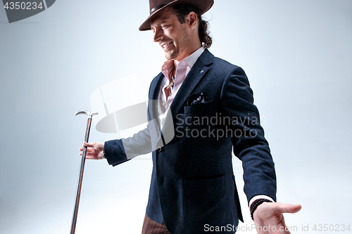 Image of The mature man in a suit and hat holding cane.