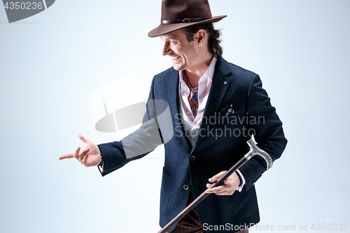 Image of The mature man in a suit and hat holding cane.