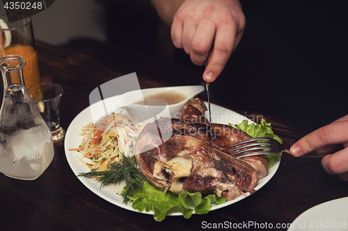 Image of Man eats tasty dish of pork shank