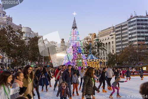 Image of Christmas fair with people ice skating on Modernisme Plaza of the City Hall of Valencia, Spain.