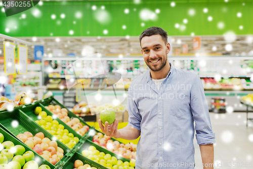 Image of happy man buying green apples at grocery store