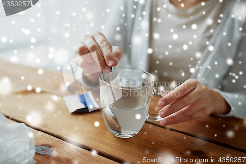 Image of ill woman stirring medication in cup with spoon