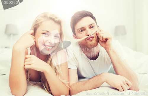 Image of happy couple lying in bed at home