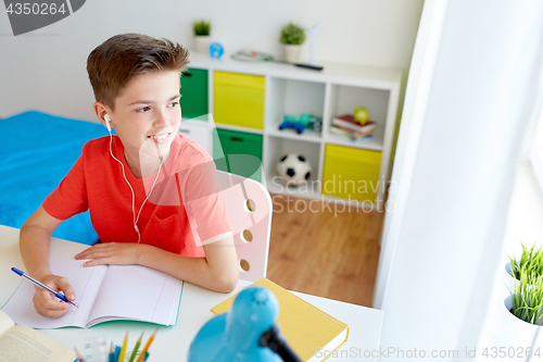 Image of happy student boy writing to notebook at home