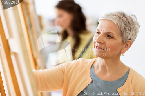 Image of woman artist with easel drawing at art school