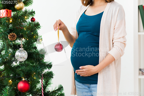 Image of pregnant woman decorating christmas tree