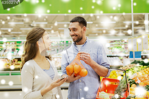 Image of happy couple buying oranges at grocery store