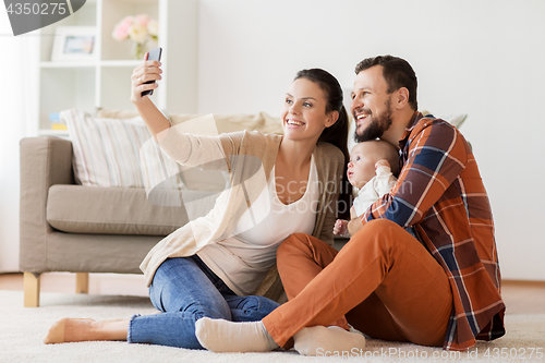 Image of mother and father with baby taking selfie at home