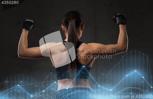 Image of young woman flexing muscles in gym