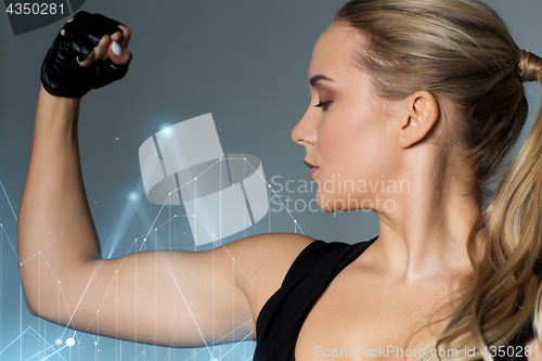 Image of close up of woman posing and showing biceps in gym