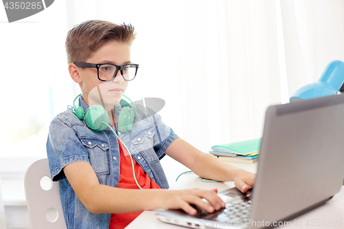 Image of student boy in glasses typing on laptop at home