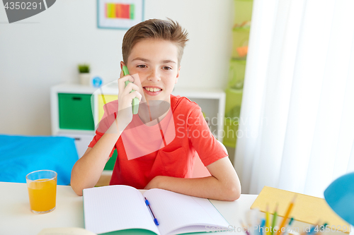 Image of student boy calling on smartphone at home