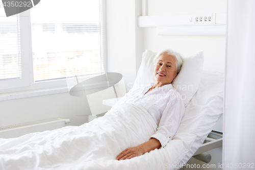 Image of smiling senior woman lying on bed at hospital ward