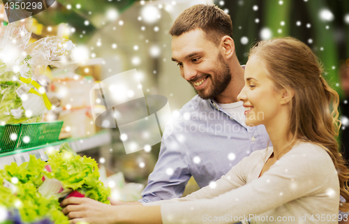 Image of happy couple buying lettuce at grocery store