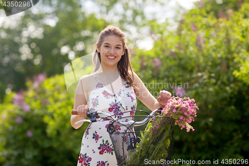 Image of happy woman riding fixie bicycle in summer park