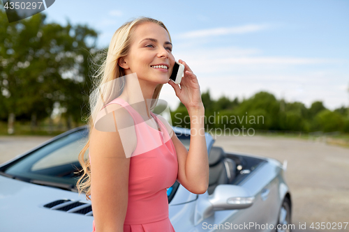 Image of woman calling on smartphone at convertible car
