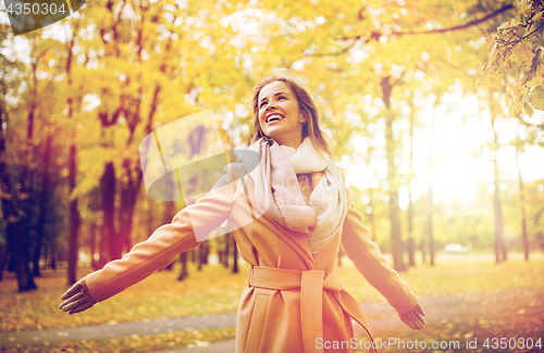 Image of beautiful happy young woman walking in autumn park