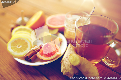 Image of ginger tea with honey, citrus and cinnamon on wood