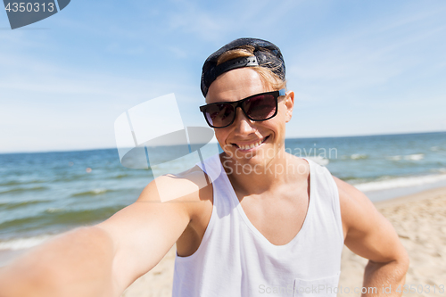 Image of man in sunglasses taking selfie on summer beach