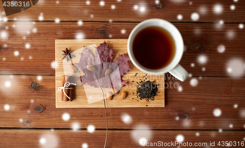 Image of cup of tea, maple leaf and almond on wooden board