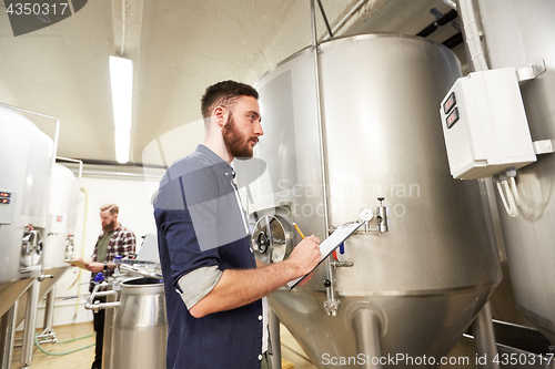 Image of men with clipboard at craft brewery or beer plant