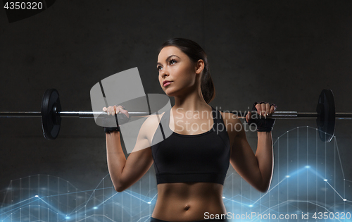 Image of young woman flexing muscles with barbell in gym