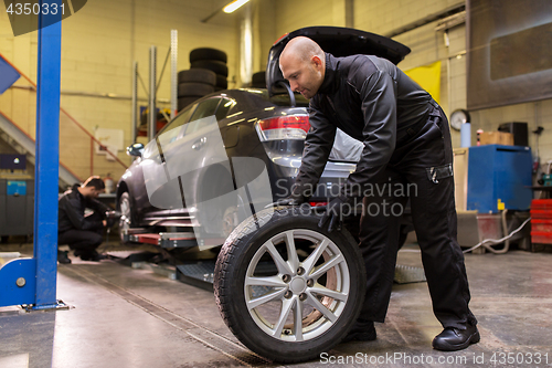 Image of auto mechanic changing car tire at workshop