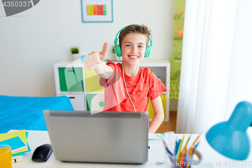 Image of boy in headphones with laptop showing thumbs up