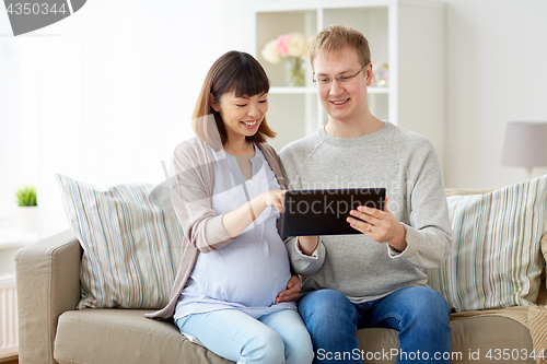 Image of husband and pregnant wife with tablet pc at home