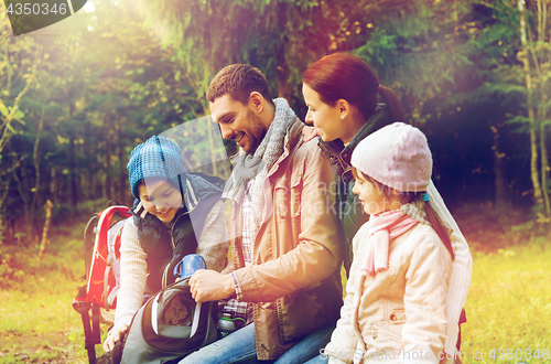 Image of happy family with backpacks and thermos at camp