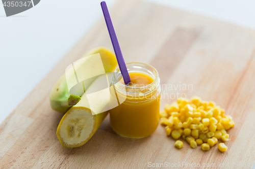 Image of jar with banana fruit puree or baby food and corn