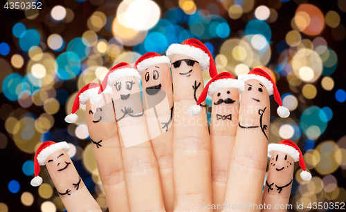 Image of close up of fingers in santa hats at christmas