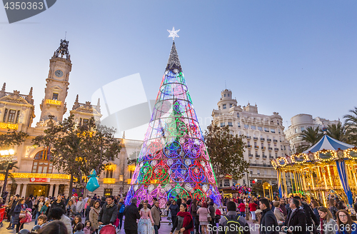 Image of Christmas fair with colorful christmas tree and carousel on Modernisme Plaza of the City Hall of Valencia, Spain.