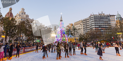 Image of Christmas fair with people ice skating on Modernisme Plaza of the City Hall of Valencia, Spain.