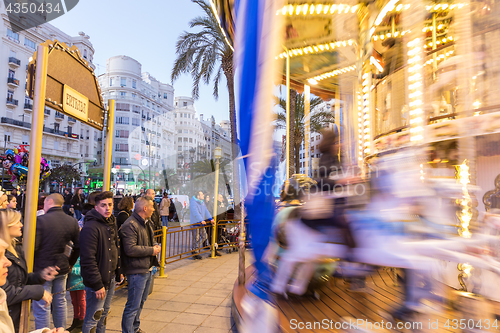 Image of Christmas fair with carousel on Modernisme Plaza of the City Hall of Valencia, Spain.