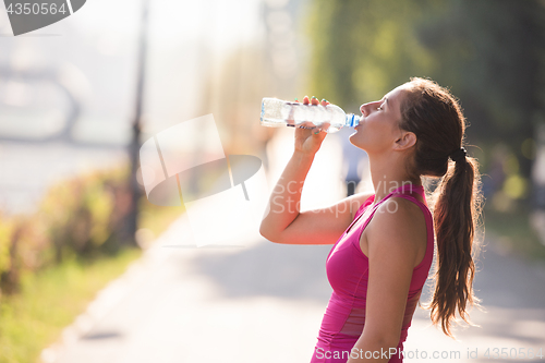 Image of woman drinking water from a bottle after jogging