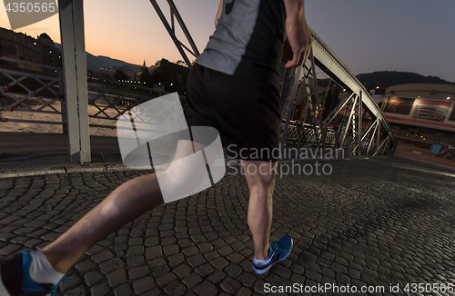 Image of man jogging across the bridge in the city