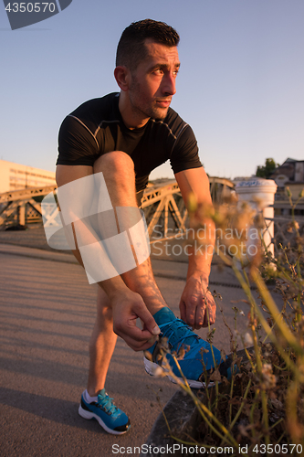 Image of man tying running shoes laces