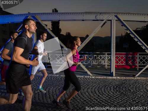 Image of young people jogging across the bridge