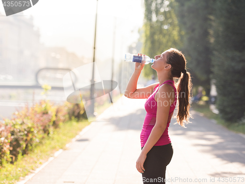 Image of woman drinking water from a bottle after jogging